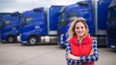 Woman professional driver in front of trucks