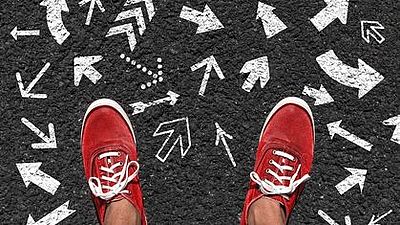 Rote Turnschuhe mit Pfeilen auf Asphalt